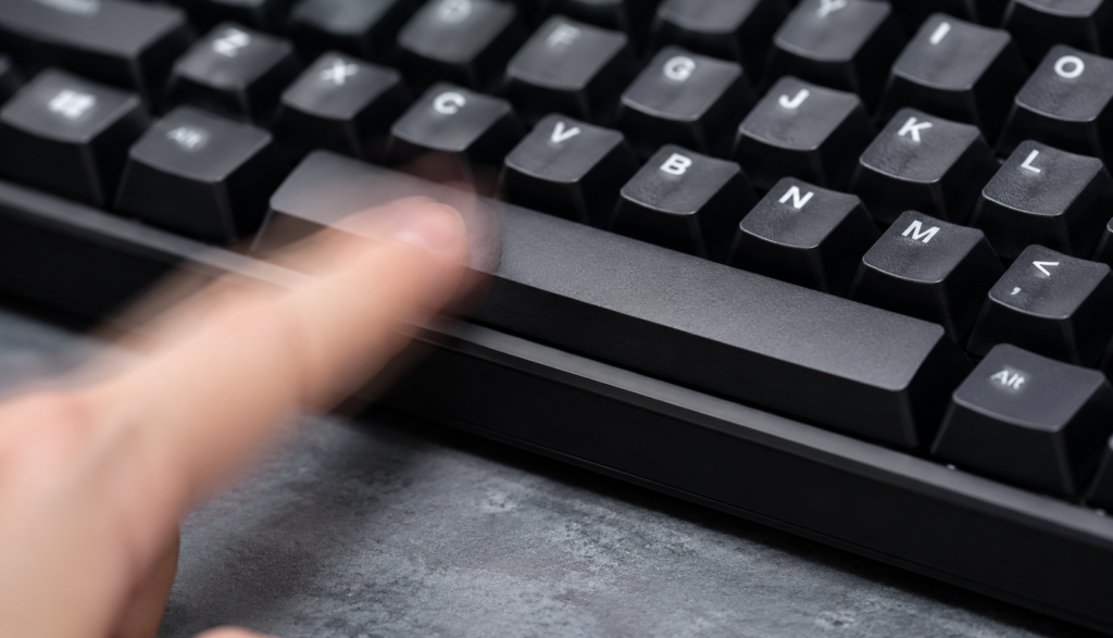 Close-up of finger rapidly tapping spacebar in motion blur showing speed and impact.